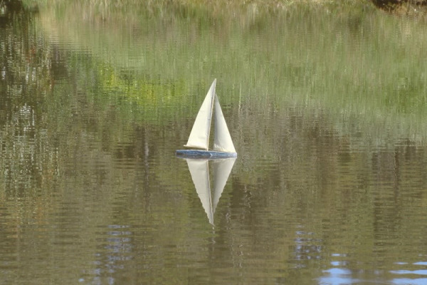 a cardboard model yacht sailing on a lake.
