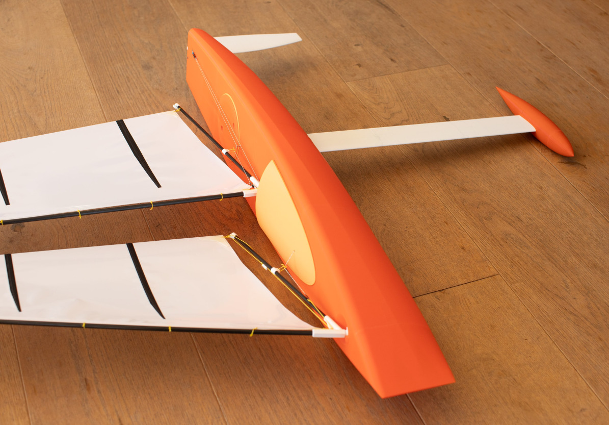 Barco de vela RC innovador Racing Sparrow RS850 con dos mástiles - el barco está tumbado de lado sobre un suelo de madera.
