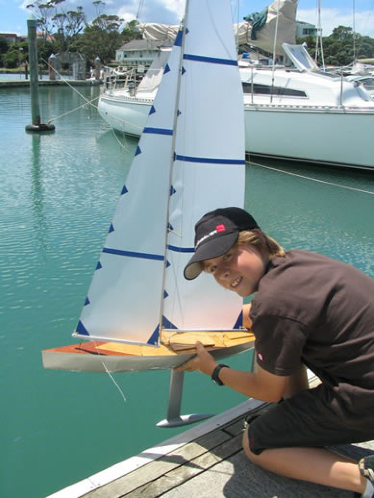 A young lad Woodwards launching a model yacht on it's maiden sail, Location: New Zealand